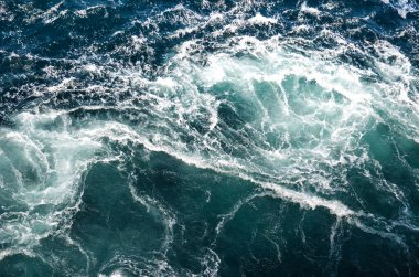 Soyut arkaplan. Deniz suyunun dalgaları su altı sivri kayalarla birleşerek girdapları oluşturur. Norveç 'in Bodo kentindeki girdaplar. Norveç