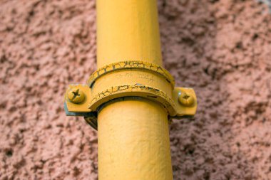 Bağlayıcılı sarı bir gaz borusu çok katlı bir binanın ön cephesi boyunca uzanıyor. Ev iç kullanım için gaza bağlıdır.