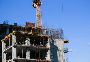 Construction of a new multi-storey building. High-rise welded work in the construction of a multi-storey building in sunny weather. Reflection of the shadows of the welders on the wall of the house.