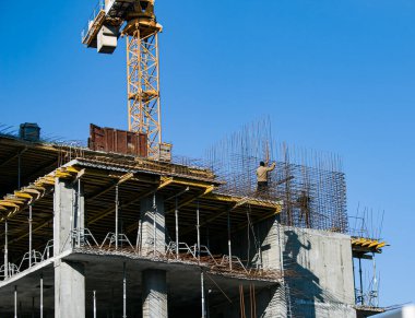 Construction of a new multi-storey building. High-rise welded work in the construction of a multi-storey building in sunny weather. Reflection of the shadows of the welders on the wall of the house.