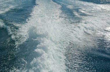 Sürat teknesinden sonra güçlü su akışı. Hızlı hareket eden motorlu teknenin arkasında su yüzeyinde iz var. Gök mavisi deniz manzarası harika. Soyut duvar kağıdı. Toprağın güzelliğini keşfedin.