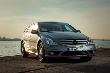 Dnepropetrovsk, Ukrayna - 03.15.2021: Mercedes-Benz R 350 otomobili gün batımında şehrin ufuk çizgisine karşı sette.