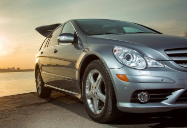 Dnepropetrovsk, Ukrayna - 03.15.2021: Mercedes-Benz R 350 otomobili, gün batımında şehrin ufuk çizgisine karşı sehpada açık bir sandık..