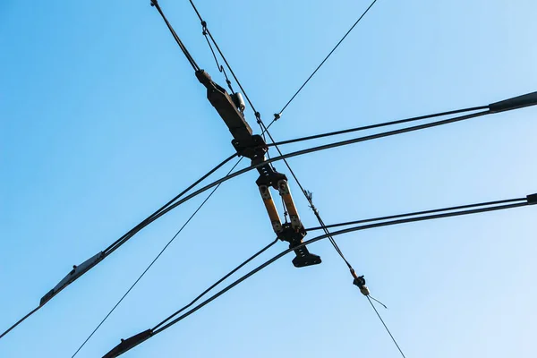 Overhead electric transmission lines against blue sky background. Industrial electric cable lines passing overhead against the clear sky background.