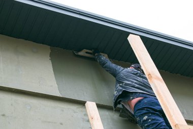 Dnepropetrovsk, Ukrayna - 03.30.2021: Dış bina duvarını sıva yapan ön cephe işçisi.