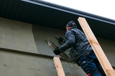 Dnepropetrovsk, Ukrayna - 03.30.2021: Dış bina duvarını sıva yapan ön cephe işçisi.