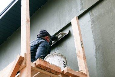 Dnepropetrovsk, Ukrayna - 03.30.2021: Dış bina duvarını sıva yapan ön cephe işçisi.