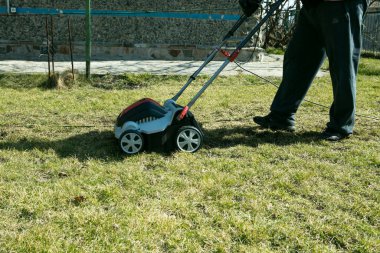 Korkutuculu havadan. Baharda çimlerin kalitesini arttırmak için bahçede bir korkuluk kullanmak. Bir işçi, Bahçıvan Çim Çim Çimen üzerinde Toprak Havacılık Makinesi.