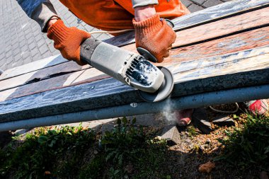 Tahta zımparalama, eski bir bankın boyasını temizleme. Resim için hazırlık. Belediye hizmetleri şehri yaz mevsimi için hazırlıyor..