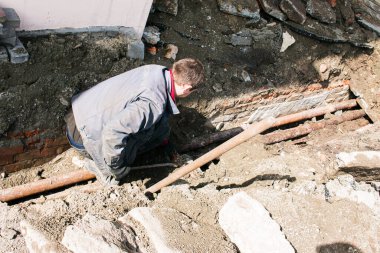 Dnepropetrovsk, Ukrayna - 03.26.2021: Su işçileri eski bir rögar kapağını açıp eski paslı boruları yenileriyle değiştirdiler.