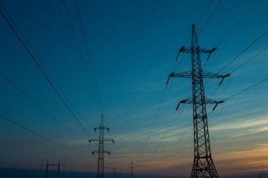 Akşamki elektrik iletim kulesinin silueti. Bir enerji santralinden bir şehre güç aktarımı.