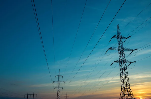 The silhouette of the evening electricity transmission pylon. Power transmission from a power plant to a city.