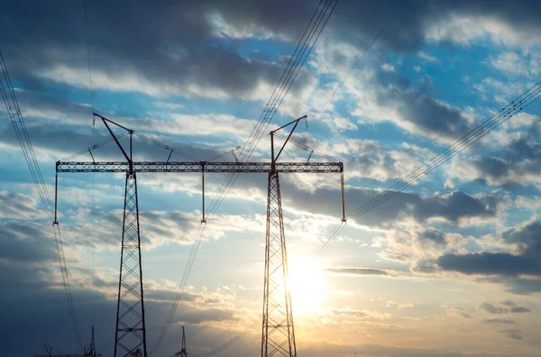 The silhouette of the evening electricity transmission pylon. Power transmission from a power plant to a city.