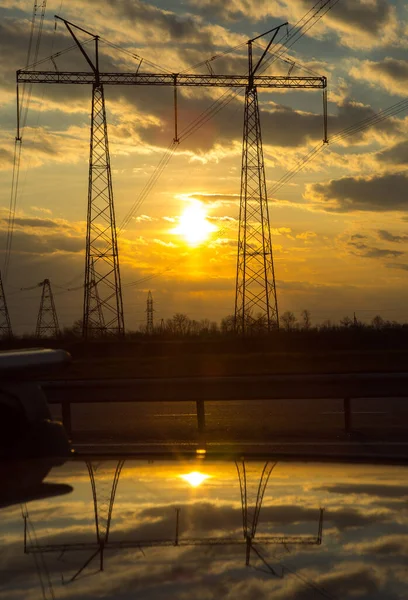 The silhouette of the evening electricity transmission pylon. Power transmission from a power plant to a city.