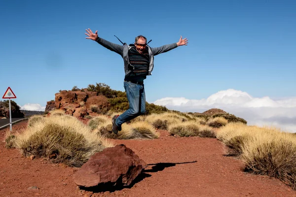 Happy tourist in full growth in a jump. The traveler jumps for joy, making a gesture of victory. The man came to rest in Tenerife.