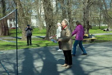 Dnepropetrovsk, Ukrayna - 04.22.2021: Parkta sağlık iyileştirici jimnastik yapan bir grup yaşlı insan. Yaşlı adamlar minitenis oynar..