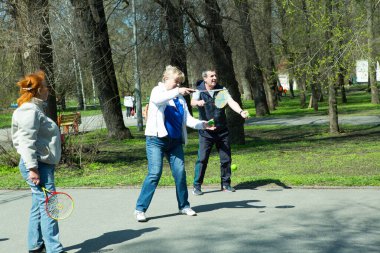 Dnepropetrovsk, Ukrayna - 04.22.2021: Parkta sağlık iyileştirici jimnastik yapan bir grup yaşlı insan. Yaşlı adamlar minitenis oynar..