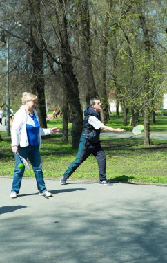 Dnepropetrovsk, Ukrayna - 04.22.2021: Parkta sağlık iyileştirici jimnastik yapan bir grup yaşlı insan. Yaşlı adamlar minitenis oynar..