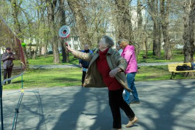 Dnepropetrovsk, Ukrayna - 04.22.2021: Parkta sağlık iyileştirici jimnastik yapan bir grup yaşlı insan. Yaşlı adamlar minitenis oynar..