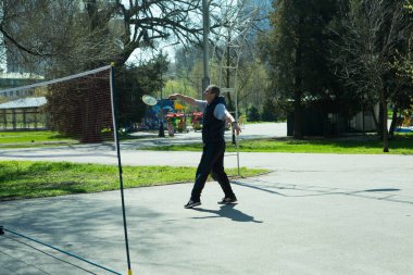 Dnepropetrovsk, Ukrayna - 04.22.2021: Parkta sağlık iyileştirici jimnastik yapan bir grup yaşlı insan. Yaşlı adamlar minitenis oynar..