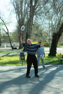 Dnepropetrovsk, Ukrayna - 04.22.2021: Parkta sağlık iyileştirici jimnastik yapan bir grup yaşlı insan. Yaşlı adamlar minitenis oynar..