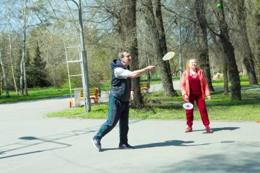 Dnepropetrovsk, Ukrayna - 04.22.2021: Parkta sağlık iyileştirici jimnastik yapan bir grup yaşlı insan. Yaşlı adamlar minitenis oynar..