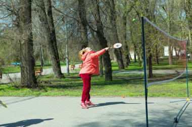 Dnepropetrovsk, Ukrayna - 04.22.2021: Parkta sağlık iyileştirici jimnastik yapan bir grup yaşlı insan. Yaşlı adamlar minitenis oynar..