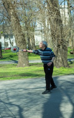 Dnepropetrovsk, Ukrayna - 04.22.2021: Parkta sağlık iyileştirici jimnastik yapan bir grup yaşlı insan. Yaşlı adamlar minitenis oynar..