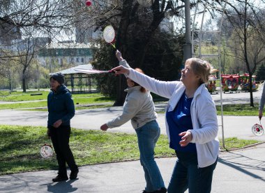 Dnepropetrovsk, Ukrayna - 04.22.2021: Parkta sağlık iyileştirici jimnastik yapan bir grup yaşlı insan. Yaşlı adamlar minitenis oynar..