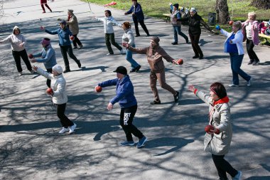 Dnepropetrovsk, Ukrayna - 04.22.2021: Parkta sağlık ve spor yapan bir grup yaşlı insan. Yaşlı insanlar bir topla egzersiz yaparlar..