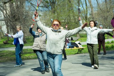 Dnepropetrovsk, Ukrayna - 04.22.2021: Parkta sağlık ve spor yapan bir grup son sınıf öğrencisi. Yaşlı adamlar tenis topu ve raket egzersizleri yapar..