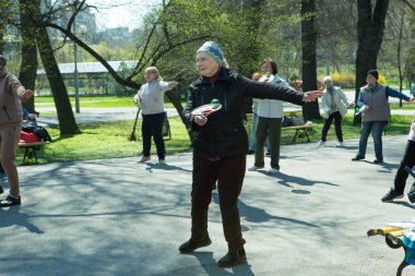 Dnepropetrovsk, Ukrayna - 04.22.2021: Parkta sağlık ve spor yapan bir grup son sınıf öğrencisi. Yaşlı adamlar tenis topu ve raket egzersizleri yapar..