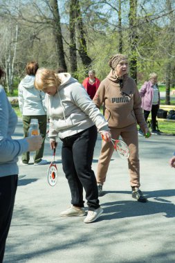 Dnepropetrovsk, Ukrayna - 04.22.2021: Parkta sağlık ve spor yapan bir grup son sınıf öğrencisi. Yaşlı adamlar tenis topu ve raket egzersizleri yapar..
