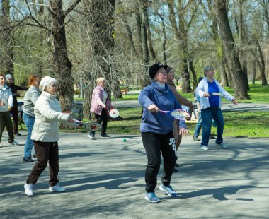 Dnepropetrovsk, Ukrayna - 04.22.2021: Parkta sağlık ve spor yapan bir grup son sınıf öğrencisi. Yaşlı adamlar tenis topu ve raket egzersizleri yapar..