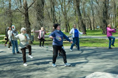 Dnepropetrovsk, Ukrayna - 04.22.2021: Parkta sağlık ve spor yapan bir grup son sınıf öğrencisi. Yaşlı adamlar tenis topu ve raket egzersizleri yapar..