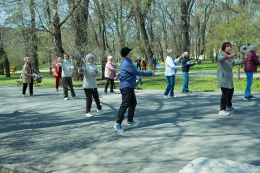Dnepropetrovsk, Ukrayna - 04.22.2021: Parkta sağlık ve spor yapan bir grup son sınıf öğrencisi. Yaşlı adamlar tenis topu ve raket egzersizleri yapar..