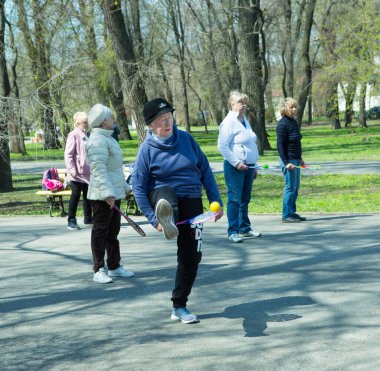 Dnepropetrovsk, Ukrayna - 04.22.2021: Parkta sağlık ve spor yapan bir grup son sınıf öğrencisi. Yaşlı adamlar tenis topu ve raket egzersizleri yapar..