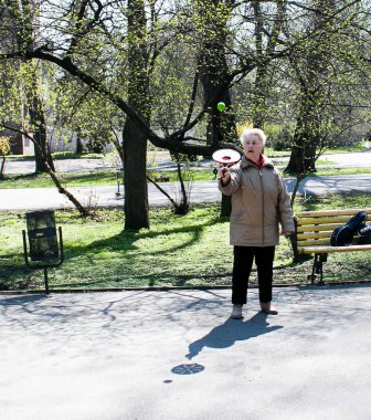 Dnepropetrovsk, Ukrayna - 04.22.2021: Parkta sağlık ve spor yapan bir grup son sınıf öğrencisi. Yaşlı adamlar tenis topu ve raket egzersizleri yapar..