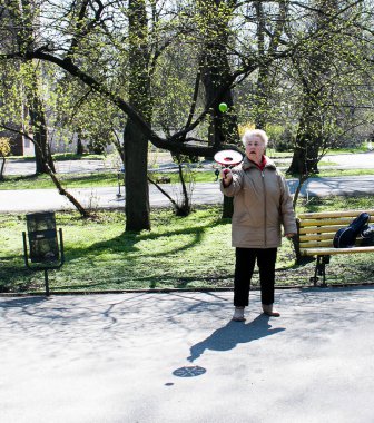 Dnepropetrovsk, Ukrayna - 04.22.2021: Parkta sağlık ve spor yapan bir grup son sınıf öğrencisi. Yaşlı adamlar tenis topu ve raket egzersizleri yapar..