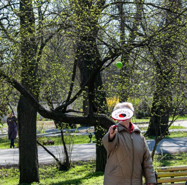 Dnepropetrovsk, Ukrayna - 04.22.2021: Parkta sağlık ve spor yapan bir grup son sınıf öğrencisi. Yaşlı adamlar tenis topu ve raket egzersizleri yapar..