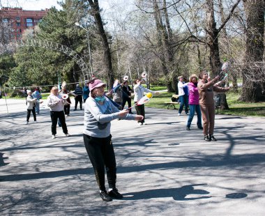 Dnepropetrovsk, Ukrayna - 04.22.2021: Parkta sağlık ve spor yapan bir grup son sınıf öğrencisi. Yaşlı adamlar tenis topu ve raket egzersizleri yapar..