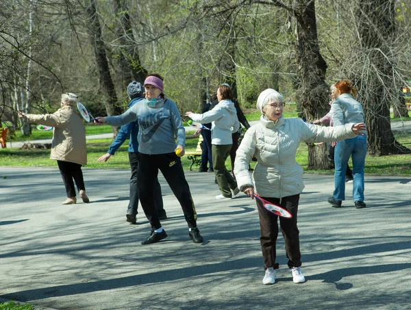 Dnepropetrovsk, Ukrayna - 04.22.2021: Parkta sağlık ve spor yapan bir grup son sınıf öğrencisi. Yaşlı adamlar tenis topu ve raket egzersizleri yapar..