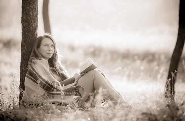 Beautiful woman with a book in her hands. A woman in nature enjoys reading.