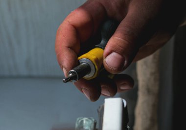 Bir adam plastik bir pencere veya kapıyı tornavida ve özel bir çekiçle düzeltiyor. Erkek elleri yakın..