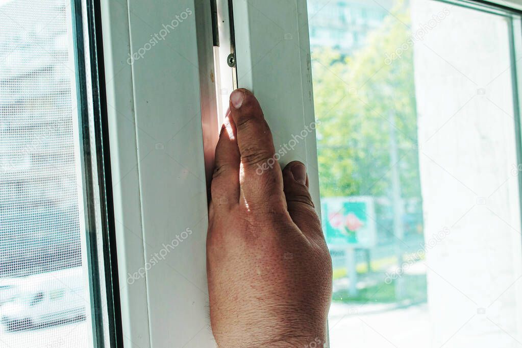 A man straightens a plastic window or door with a screwdriver and a special mallet. Male hands close up.