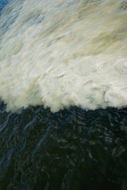 Lağım borularından akan kirli portakal suyu nehir suyuyla karışıyor. İki farklı su akıntısı arasındaki temiz sınır. Çevre kirliliği teması.