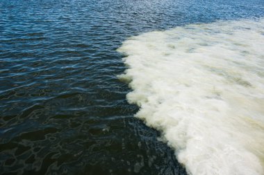 Lağım borularından akan kirli portakal suyu nehir suyuyla karışıyor. İki farklı su akıntısı arasındaki temiz sınır. Çevre kirliliği teması.