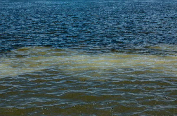 下水パイプラインからの汚れたオレンジの水は川の水と混合する 2つの異なる水流の間の明確な境界線 環境汚染のテーマ — ストック写真