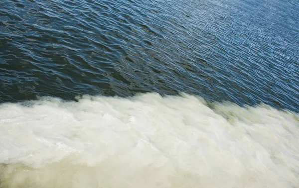 下水パイプラインからの汚れたオレンジの水は川の水と混合する 2つの異なる水流の間の明確な境界線 環境汚染のテーマ — ストック写真