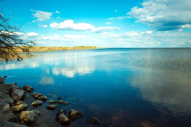 Bulutlu göl, mavi gökyüzü ve su yansımaları. Kakhovskoe rezervuarı, Ukrayna.